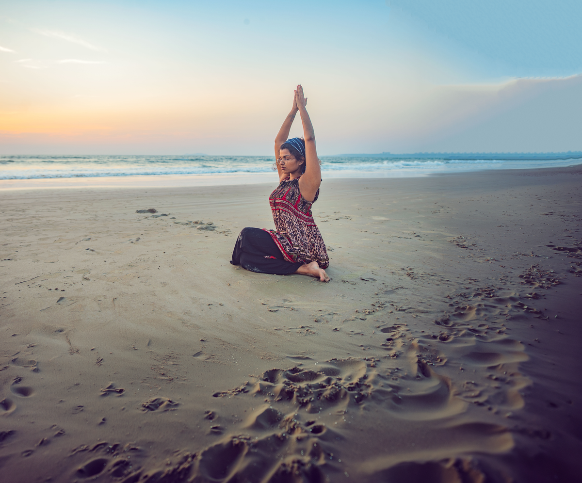 Gayathri sitting in meditation on the shore at sunrise
